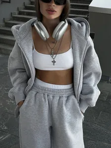 Full view of a woman wearing a gray oversized tracksuit with large silver headphones