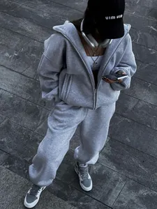 Detail of a grey oversized zip-up hoodie and matching joggers set in an urban setting.