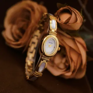 Elegante reloj dorado con inserciones de concha blanca y esfera de nácar refinada