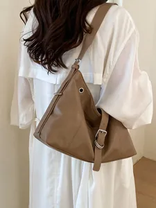 Stylish brown soft leather shoulder bag for women worn by a model in a white dress