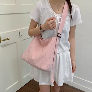 Close-up of a pink canvas bag with silver star patterns worn with a white summer dress