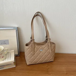 Elegante beige gesteppte Ledertasche auf einem Holztisch mit stilvoller Dekoration präsentiert.