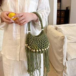 Detailed view of a green bohemian woven handbag featuring white wooden beads and long tassels.