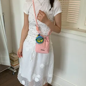 Detailed shot of a stylish pink drawstring bucket bag worn by a model for summer outfits.