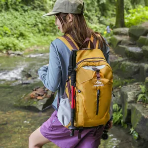 Gros plan d'un sac à dos de randonnée jaune moutarde porté par un mannequin en forêt