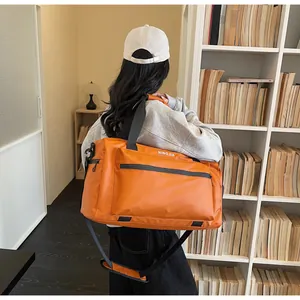 Large orange travel duffel bag for gym and hiking carried by model in a library scene