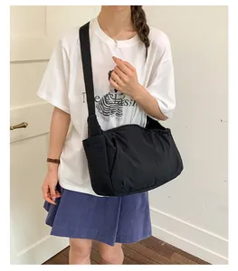 Detail view of a black lightweight crossbody tote bag worn by a casual model.