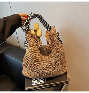 Vue détaillée du sac de plage en paille tressée avec sa poignée en foulard rayé