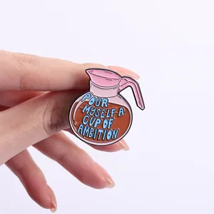 Close-up detail of a coffee pot enamel pin featuring the text Pour Myself a Cup of Ambition