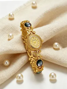 Elegante reloj de pulsera dorado con concha natural sobre fondo de perlas y tela
