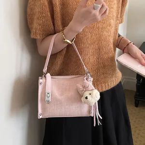 Close-up detail of a pink textured handbag featuring a cute puppy plush charm and bow