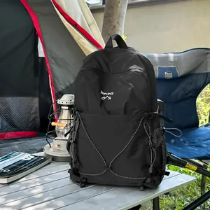 Sac à dos de camping noir robuste avec logo montagne sur une table de camping.