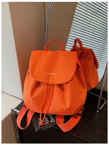 Vibrant orange checkered small backpack displayed with a mirror reflection and book prop