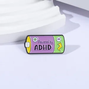 Detailed view of a battery-shaped enamel pin with Powered by ADHD text and vibrant colors.