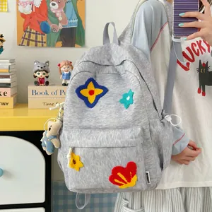 Close-up of grey school backpack featuring vibrant colorful plush flower patches