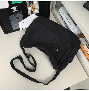 Close-up detail of the black minimalist canvas messenger bag placed on a clean office desk area