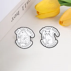 Detailed close-up shot of capybara and cat enamel pins with Spanish quote engravings