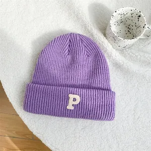 Detailed view of a purple knitted beanie featuring a white embroidered letter P on the brim