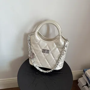 Close-up of champagne quilted bucket bag with silver chain strap and charm detail.