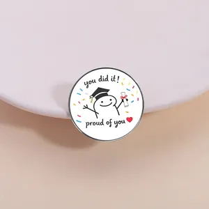 Detail shot of a graduation cartoon figure enamel pin with motivational text.