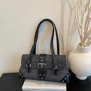 Detailed view of a textured grey baguette bag featuring a black buckle strap and silver studs