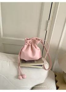 Detail of a candy pink drawstring bucket bag on a minimalist white sofa decor