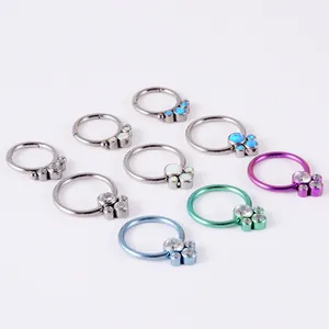 Macro detail of multicolored G23 titanium hoop nose rings featuring opal and crystal stones