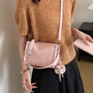 Close-up detail of a stylish pink textured crossbody pillow bag featuring a cute dog charm