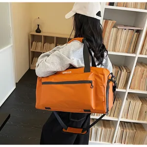 Large capacity orange travel duffel bag for fitness and hiking carried by model