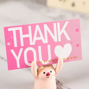 Detailed view of a pink thank you for your purchase card held by a cute piglet figurine