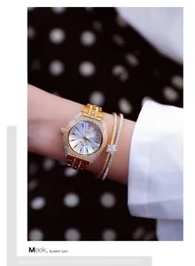 Detalle de cerca del reloj dorado BS Bee Sister con pedrería y pulseras en la muñeca