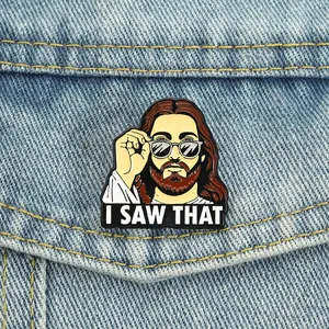 Funny Jesus enamel pin wearing sunglasses with 'I SAW THAT' slogan pinned on denim jacket