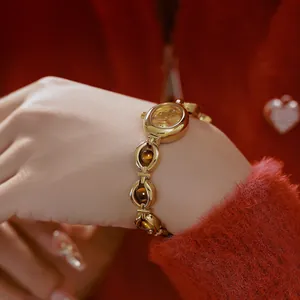 Primer plano de reloj vintage dorado para mujer con brazalete de piedras ojo de tigre