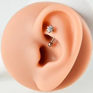 Close-up of G23 titanium curved barbell earring with flower zircon on silicone ear model.
