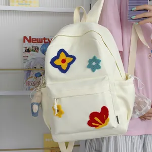 Close-up of a cream-colored school backpack with colorful plush flower patches