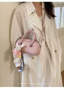 Vue détaillée du sac bowling en cuir vernis rose avec joli pendentif lapin tricoté et sangle.