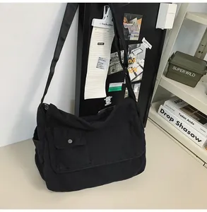 Minimalist black canvas messenger bag with front pocket for everyday casual use