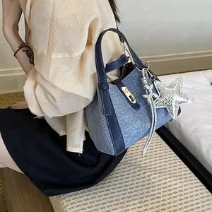 Close-up view of a stylish blue denim texture bucket bag with a silver star charm accessory.