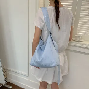 Back view of a model wearing a light blue canvas tote bag with silver stars