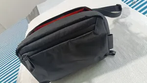 Vista detallada de una riñonera deportiva negra impermeable con forro interior rojo