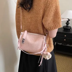 Side view of pink textured crossbody pillow bag worn by a model in a cozy indoor setting