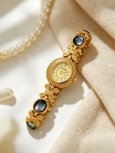 Vista detallada del reloj de pulsera dorado con piedras de concha de abulón negro irisado.