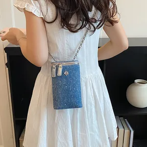Model wearing a blue denim crossbody phone bag with chain strap and rhinestone detail