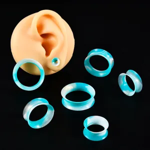 Tunnel per orecchie in silicone marmorizzato blu e bianco su modello di orecchio.