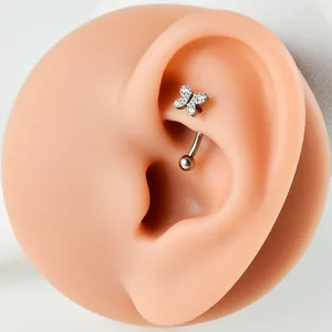 Detailed close-up of a butterfly-shaped G23 titanium ear piercing with zirconia stones