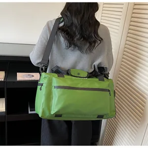 Detailed view of the large green travel bag worn by a model in a cozy indoor setting.