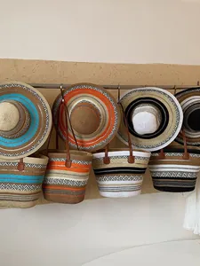 Kollektion großer Stroh-Einkaufstaschen und passender Strandhüte an einer Wand.