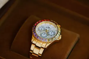 Detailed macro view of gold luxury women's watch with rainbow stone bezel and crystal dial