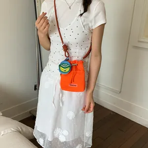 Orange mesh crossbody bucket bag with brown rope strap worn by a model