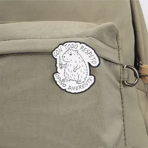 Close-up of a funny capybara brooch with Spanish text on a durable green canvas backpack
